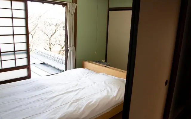 Kawazoi room with a bed and riverside view（窓辺のベッドと川沿いの景色を望む川沿いの客室）