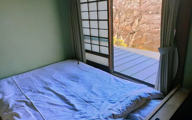 Bed and riverside window in Kawazoi room（川沿いの景色が見える窓辺とベッド）