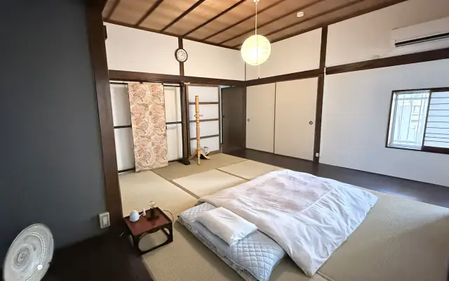 Wide view of Take room with tatami and futon bedding（畳と布団を備えた竹の和室）