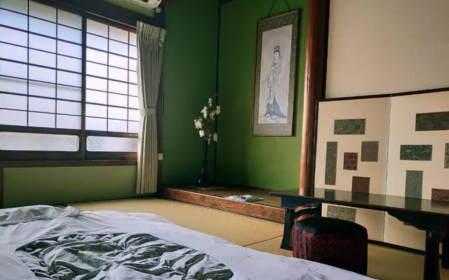 Tsubaki tatami room with deep green walls and futon bedding（深い緑の壁と布団を備えた椿の和室）